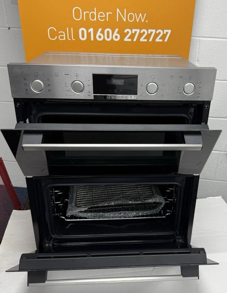 Bosch Series 4 NBS533BS0B Electric Built-Under Electric Double Oven in Stainless Steel from HomeWise Appliances. Showroom photo showing front of oven with doors open. In front of a call to action sign. Call 01606 272727